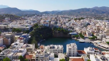 Agios Nikolaos, Girit 'in hava manzarası beyaz ve pastel binaları, terracotta çatılarını, yeşillikleri ve etrafındaki tepeleri ve dağları gösteriyor..