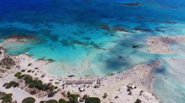 Girit 'teki Elafonisi Sahili' nin havadan görünüşü turkuaz suları, kumsalları, kayalık adaları ve sakin sahil şeridinde düzgün kamera hareketlerini gösteriyor..