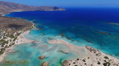 Yunanistan 'ın Girit kentindeki Elafonisi Sahili' nin üzerinde pürüzsüz bir tava, kıyı boyunca pembe kumlar, turkuaz sular, kayalık adalar ve engebeli dağları gösteriyor..