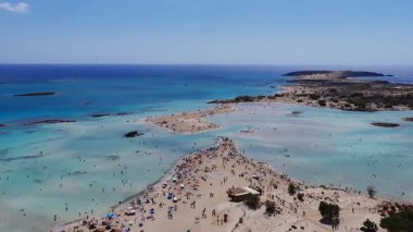 Girit 'teki Elafonisi Sahili' nin yavaş bir hava görüntüsü, pembe kum, turkuaz sular, ziyaretçiler, kumsallar, adalar ve derin mavi ufku gösteriyor..