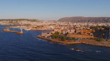 Girit, Yunanistan, Chania 'nın altın saatindeki hava manzarası. Kamera suyun üzerinde hareket ediyor, Venedik limanını, deniz fenerini ve sahil şeridini gösteriyor..
