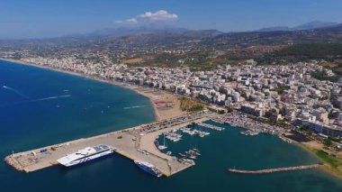 Yavaş bir tavada, Rethymno 'nun beyazlatılmış binaları, tekneleri, kumlu plajları, turkuaz suları ve berrak mavi gökyüzünün altındaki yuvarlanan tepeleri gözler önüne seriliyor..