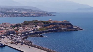 Pürüzsüz hareketli hava manzarası Rethymno 'nun Fortezza' sını, Akdeniz kıyı şeridini, bembeyaz binaları ve dağlık zemin.