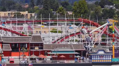 Kaliforniya 'daki Santa Cruz sahil şeridi manzarası. Dev Ayı Lunaparkı hız treni hareket halindeki teleferikler, palmiye ağaçları ve renkli gösteriler..
