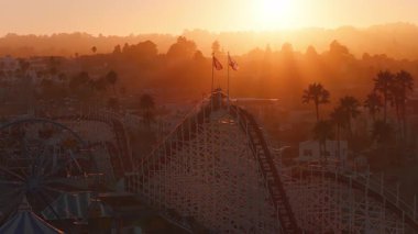 Gün batımında Santa Cruz, California 'nın havadan görünüşü. Dev Ayı Lunaparkı hız treni, dönme dolap, sallanan bayraklar ve altın ışıkta palmiye ağaçları. GTA biçimi.