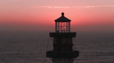Günbatımında Kaliforniya 'da Güvercin Noktası Deniz Feneri. Güneş batarken, sakin okyanus yansımaları ve canlı turuncu ve pembe gökyüzü..