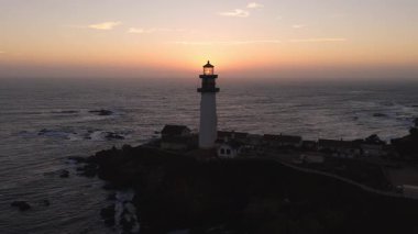 Güneş Pasifik Okyanusu 'nun üzerinde, Pigeon Point Deniz feneri yakınlarında batıyor. Gökyüzüne sıcak renkler ve dalgalı dalgalar serpiştiriyor..