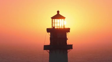 Gün batımında Pigeon Point Deniz fenerini kapatın. Canlı turuncu ve sarı renkler, ufukta kısmi güneş ve arka planda soluk bir okyanus olsun..