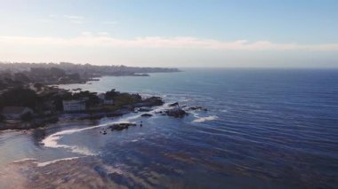 Monterey, California yakınlarındaki Pasifik Okyanusu kıyı şeridi havadan görünüyor. Kamera sahneyi çekerken dalgalar kayalık sahil boyunca yavaşça hareket eder..