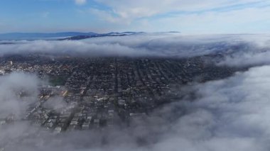 San Francisco 'nun havadan görünüşü bulutlar sürükleniyor, şehrin sokaklarını, binalarını, San Francisco Körfezi' ni ve çevresindeki tepeleri gözler önüne seriyor..