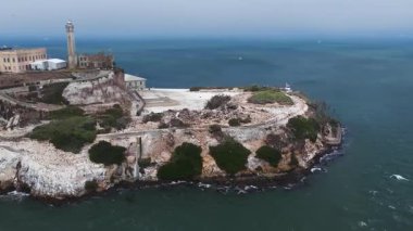 Alcatraz Adası 'nın pürüzsüz üstgeçişi, kayalık arazi, ikonik hapishane, deniz feneri, yeşillik ve San Francisco Körfezi' nin mavi suları..