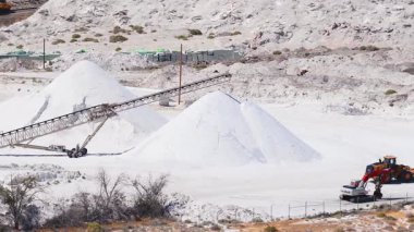 Nevada 'daki tuz madenlerinde beyaz tuz tepecikleri, taşıma sistemi, kazıcı, yükleyici ve kurak bir arazide bir yük treni görülüyor..