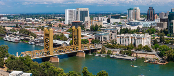 Вид с воздуха на Сакраменто, Калифорния, с золотым Тауэрским мостом через реку Сакраменто, городские здания и Капитолий штата вдали.