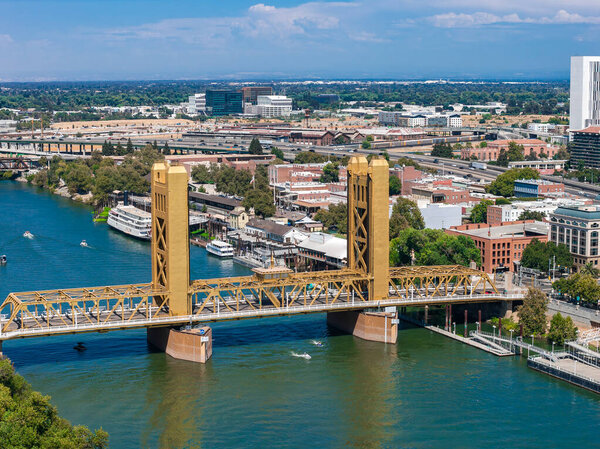 Вид с воздуха на Сакраменто, Калифорния, с золотым Тауэрским мостом через реку Сакраменто, окруженный городскими зданиями и улочками, выложенными деревьями.