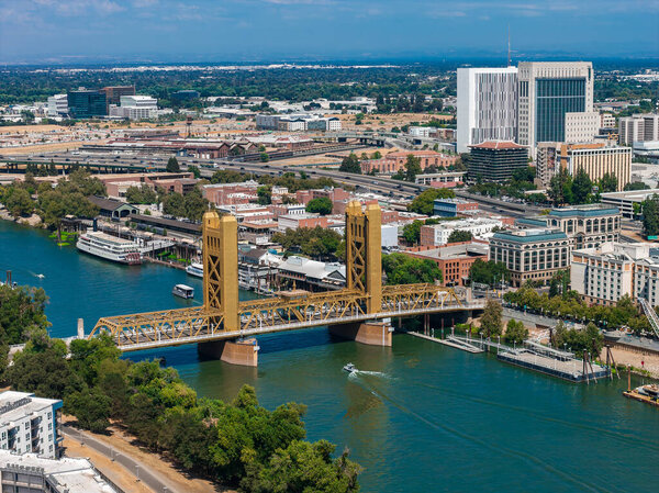 Вид с воздуха на Сакраменто, Калифорния, с золотым мостом через реку Сакраменто, городскими зданиями, Капитолием штата и пышной зеленью.