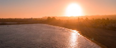 Santa Cruz, California 'nın hava manzarası, gün batımında Dev Ayı Lunapark treni, sahil kaldırımı, sakin okyanus suları ve puslu bir tepe zemin..