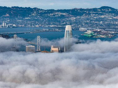 San Francisco 'da Satış Gücü Kulesi, Bay Köprüsü kısmen görünür ve arka planda liman tesisleri yer alıyor..