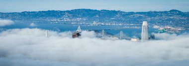 San Francisco 'nun havadan görünüşü ve şehrin bazı kısımlarında sis var. Körfez Köprüsü, Satış Gücü Kulesi ve Transamerica Piramidi görünür durumda..