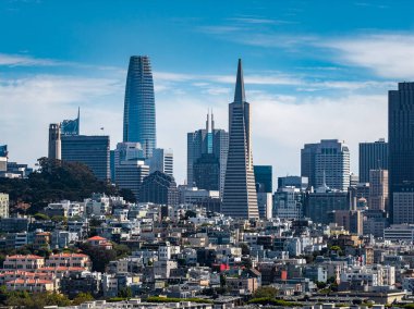 San Francisco şehir merkezinde Transamerica Piramidi, Satış Gücü Kulesi ve açık mavi gökyüzü altında dağınık bulutlu konut binalarının görüntüsü.