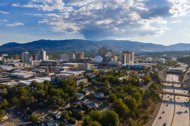 Reno, Nevada 'nın hava görüntüleri, şehir merkezindeki gökyüzünü kumarhanelerle, Gümüş Miras' ın beyaz kubbesi, yerleşim alanları, bir otoyol ve dağlarla gösteriyor..