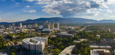 Reno, Nevada 'nın hava manzarası, şehir merkezindeki yüksek binalar, kumarhaneler, Ulusal Bowling Stadyumu, yeşillik ve Sierra Nevada dağları..