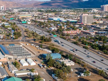 Reno, Nevada 'nın hava görüntüleri, bir otoyol, şehir merkezindeki binalar, Grand Sierra Resort, kurak arazi ve arka plandaki uzak dağları gösteriyor..