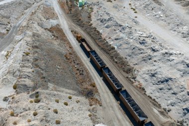 Aerial view of a salt mining site in Nevada featuring a train on a dirt track, mining equipment, storage areas, and rugged, arid surroundings.