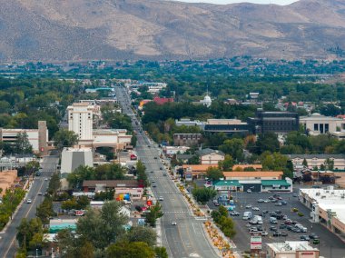 Carson City, Nevada 'nın havadan görünüşü, merkezi bir yol, ticari binalar, beyaz bir kubbe ve arka planda kurak tepeler gösteriyor..