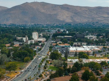 Carson City, Nevada üzerinde merkezi bir yol, kentsel alanlar, yeşillik ve ufukta hüküm süren kurak dağlar yer alıyor..