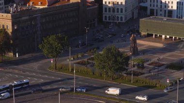 Riga, Letonya 'nın hava manzarası trafik, tramvay, tarihi binalar, ağaçlı bir park ve hareket halindeki yayaları gösteriyor..