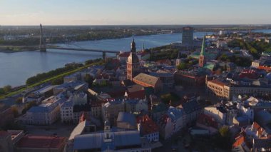 Riga, Letonya 'nın havadan görünüşü, eski kasaba, Daugava Nehri' ni, hareket eden bir teknesi, bir köprüsü ve altın saatinde Ulusal Kütüphane ile gösteriyor..