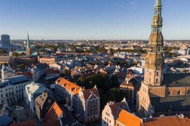 Riga, Letonya 'nın havadan görünüşü, Aziz Peter Kilisesi kulesi, eski kasabanın kırmızı kiremitli çatıları, Riga Katedrali ve sıcak güneş ışığı altında modern binalar..