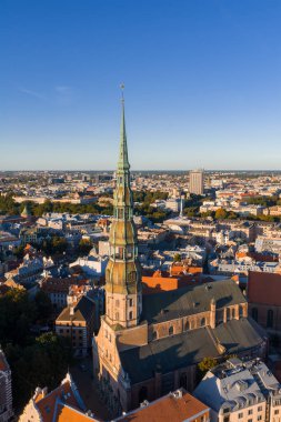 Riga, Letonya 'nın havadan görünüşü, süslü kulesi, tarihi kırmızı kiremitli çatıları ve berrak mavi gökyüzü altındaki modern binaları ile Aziz Peter Kilisesi' nin.