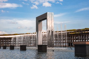 Dinamik su fıskiyeleri ile yansıtıcı metalik bir kemer çatısı yeşili olan bir şebeke ve Japonya 'nın Osaka şehrinde açık mavi bir gökyüzü..