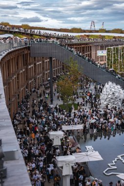 Ziyaretçiler, çok katlı ahşap bir yapı, yansıtıcı bir su özelliği ve sanatsal tesislerin yer aldığı Osaka, Japonya 'daki açık hava mekanında bir araya geldiler..