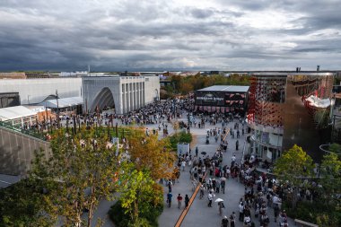 Dünya Fuarı 2025 Osaka 'da, modern mimari, ağaçlar, patikalar ve' ROBOT ve Dünya Gecesi 'yazan bir tabela ile çevrili ziyaretçiler toplandı..