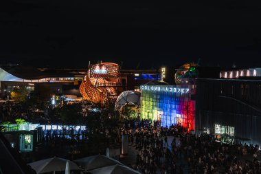 Dünya Fuarı 2025, Osaka 'da loş ışıklarla aydınlatılmış Kolombiya pavyonu. Tahta sarmal yapı ve yanan köşkler canlı bir atmosfer yaratır..