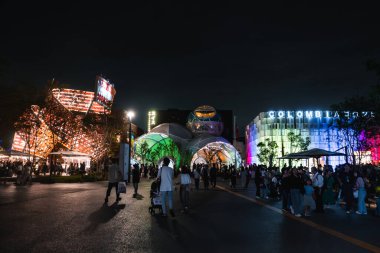 Japonya 'nın Osaka şehrinde 2025 sayılı Dünya Fuarı' na canlı bir gece manzarası. Parlayan pavyonlar, aydınlık bir Kolombiya binası ve hareketli bir atmosferde kalabalıklar..