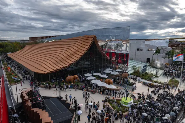 Dünya Fuarı 2025 Osaka 'da, dalgalı bir terracotta çatısı, aynalı bir bina, gerçek boyutta fil heykelleri ve uluslararası bayrakları bulunan ziyaretçiler bir araya geldiler..