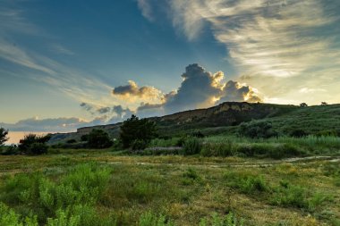 Altın renkler, Karadeniz kıyısında güneş ufukta batarken kır çiçeklerinin rengarenk bir görüntüsüyle harmanlanarak sakin bir atmosfer yaratıyor. Doğa bu güzel manzarada gelişir..