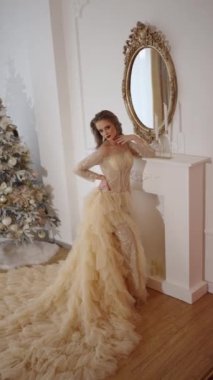 Şenlikli elbiseli çekici bir bayan aynanın yanında duruyor.