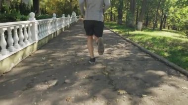 Bir adam sonbahar parkında koşar.