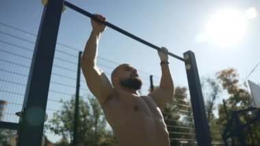 Sporcu spor alanında barfiks çekiyor.