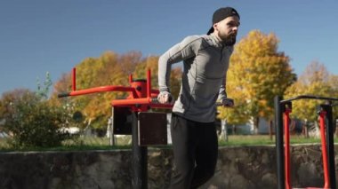 Spor sahasında barlarda şınav çeken bir sporcu, yavaş çekim, sonbahar