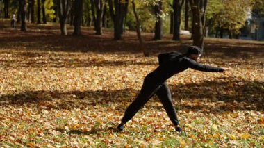 Bir adam kaslarını esnetir, temiz havada spor yapar, ağır çekimde.