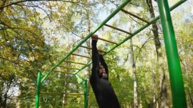 Yakışıklı bir atlet açık hava spor sahasında antrenman yapıyor. Simülatördeki ellerin kasları için egzersiz yapar.