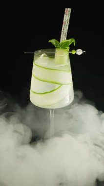 Siyah arka planda salatalık olan bir bardak alkollü kokteyl.