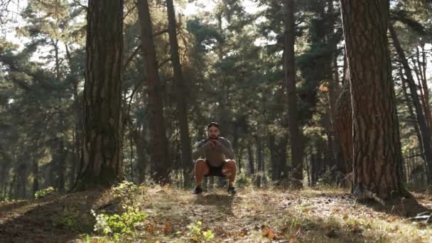 一个身穿运动服的年轻人正在树林里的树间进行体能训练 所有肌肉组的体育活动 — 图库视频影像