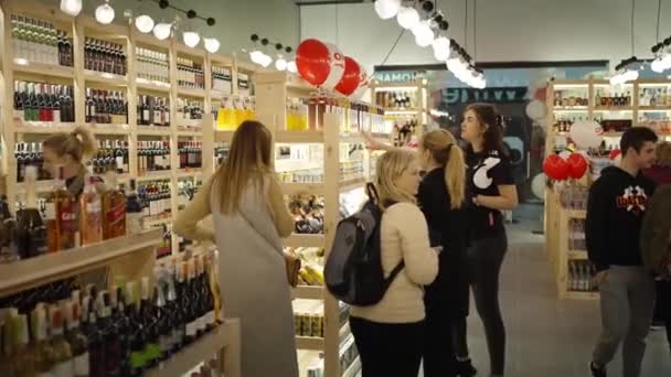 一个女人在商店里买葡萄酒 读着卖家建议她买的瓶子上的标签 在超市的酒柜上选择了一种酒精饮料 乌克兰Rivne 10月14日 — 图库视频影像