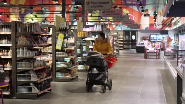 유모차에 아기를 태우고 어머니는 슈우퍼 주위를 산책하면서 제품을 어린아이가 주위에 — 비디오